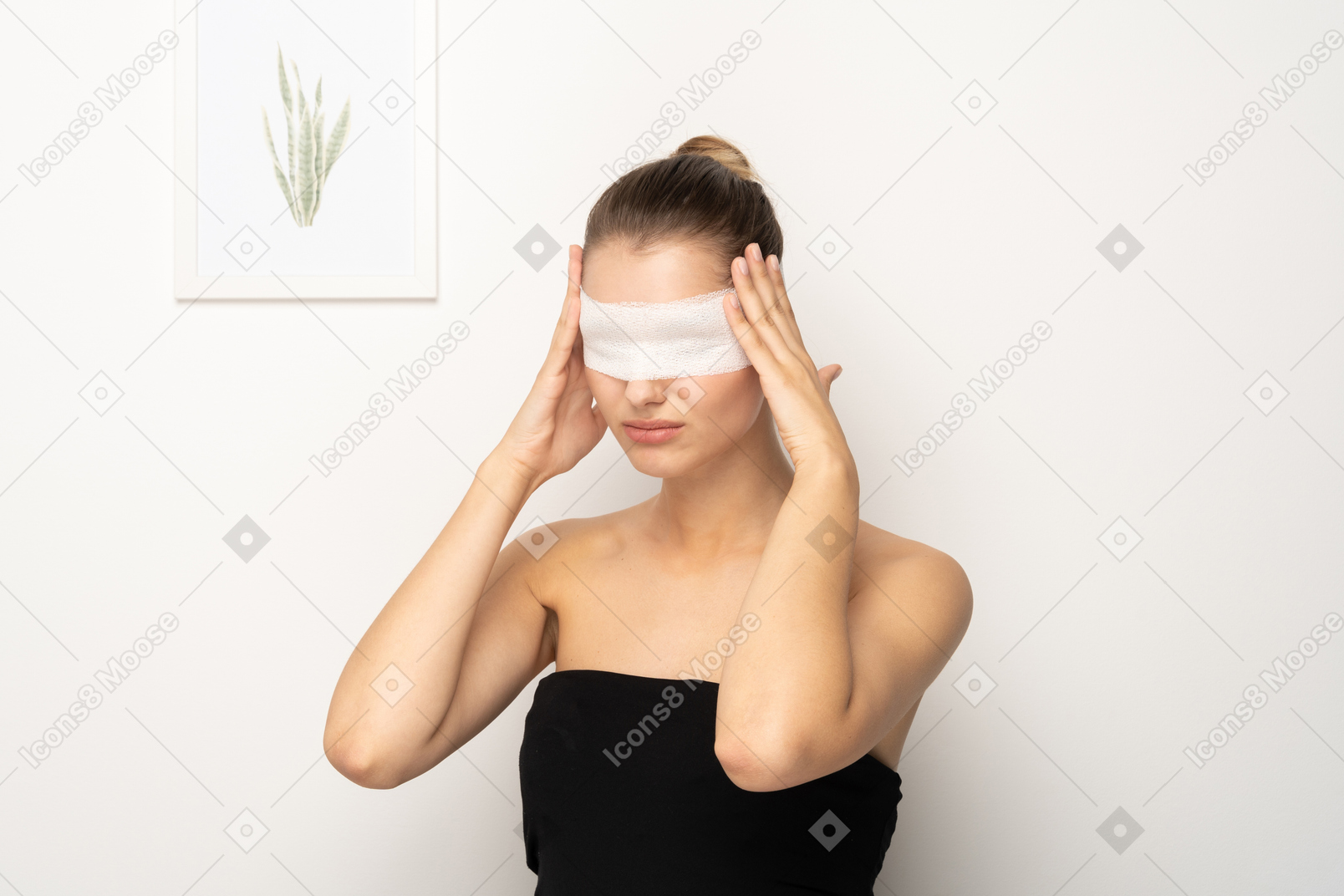 관자놀이를 만지고 있는 눈에 붕대를 감고 있는 젊은 여성