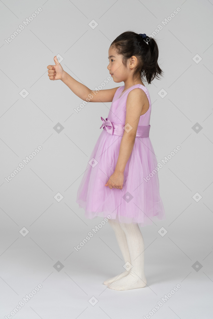 Side view of young girl giving thumbs up