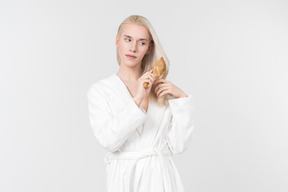 Young blond-haired man in a white bathrobe going about his morning routine