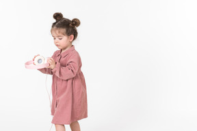 Menina criança segurando fones de ouvido-de-rosa