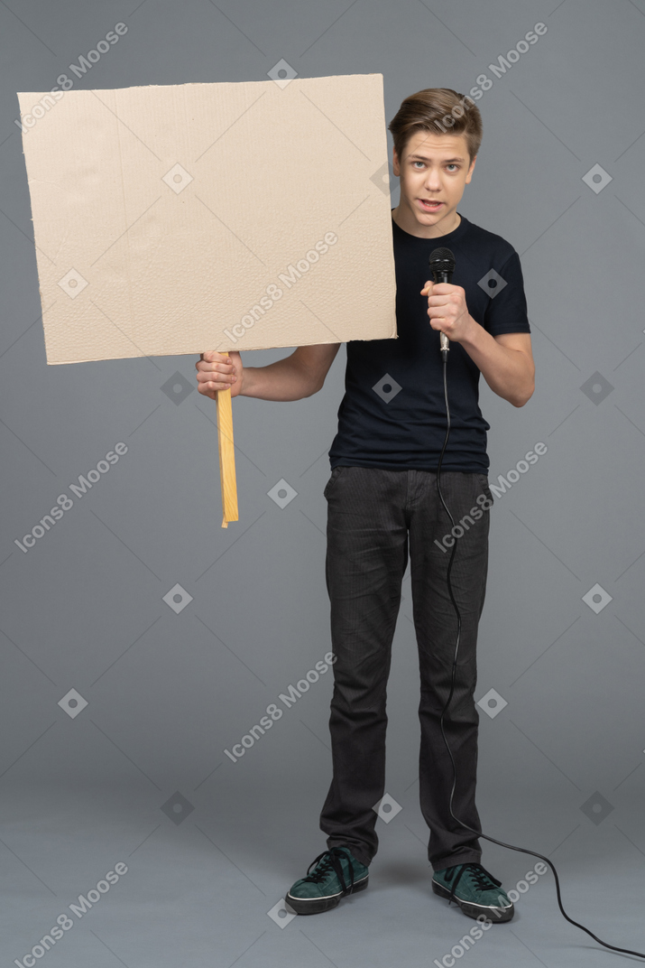 Young man speaking into a microphone and holding a poster