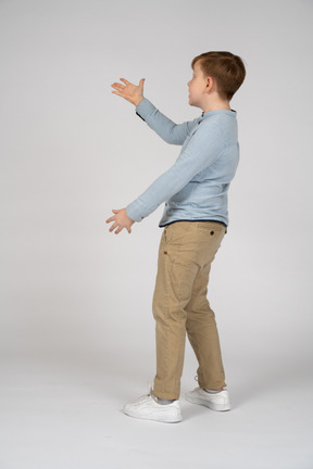 Vista lateral de um menino mostrando algo