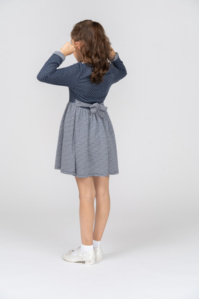 Three-quarter back view of a girl folding her ears with her fingers