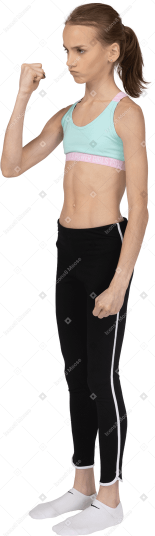 Dreiviertelansicht eines jugendlichen mädchens in der sportbekleidung, die hand hebt und faust zeigt