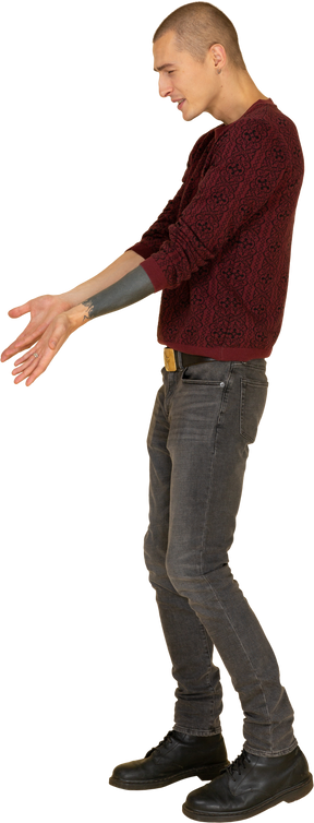Vista laterale di un giovane uomo che si lamenta in pullover rosso che tende le sue mani