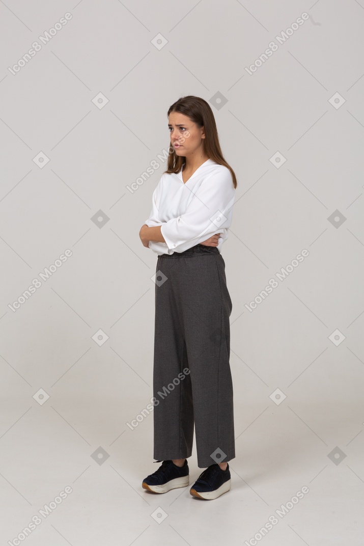 Vista di tre quarti di una giovane donna sconvolta in abiti da ufficio che si abbraccia