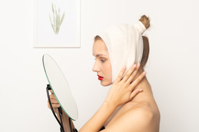 Side view of a young woman holding a mirror