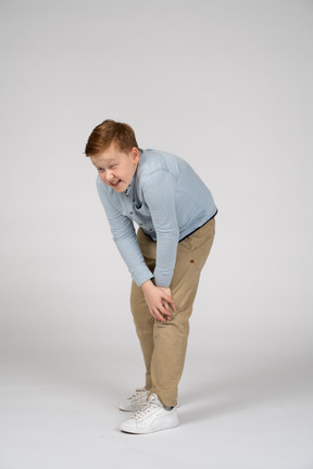 Front view of a boy bending down and touching hurting knee