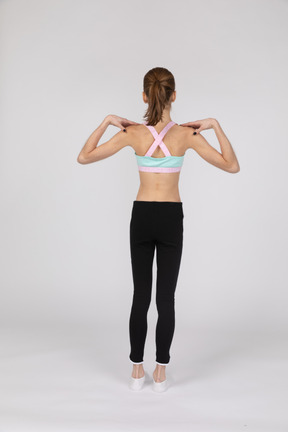 Vista traseira de uma adolescente em roupas esportivas tocando seus ombros