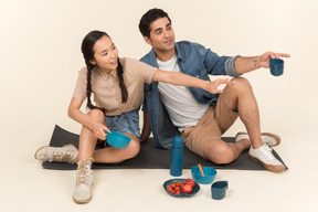 Jeune couple interracial assis sur karimat et pointant