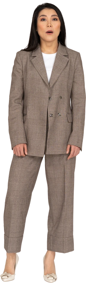 Front view of a surprised young lady in brown business suit