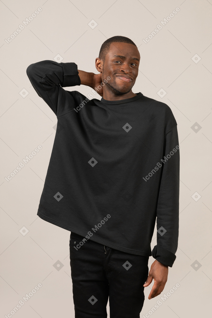 Young man scratching his neck and smiling