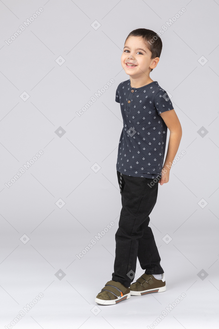 Front view of a happy boy in casual clothes walking