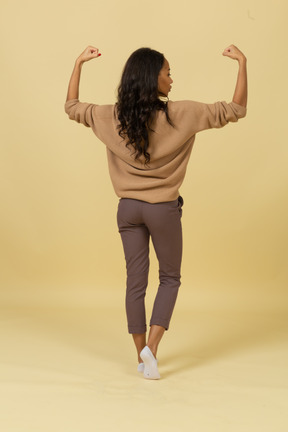 Back view of a dark-skinned young female raising hands and clenching fists