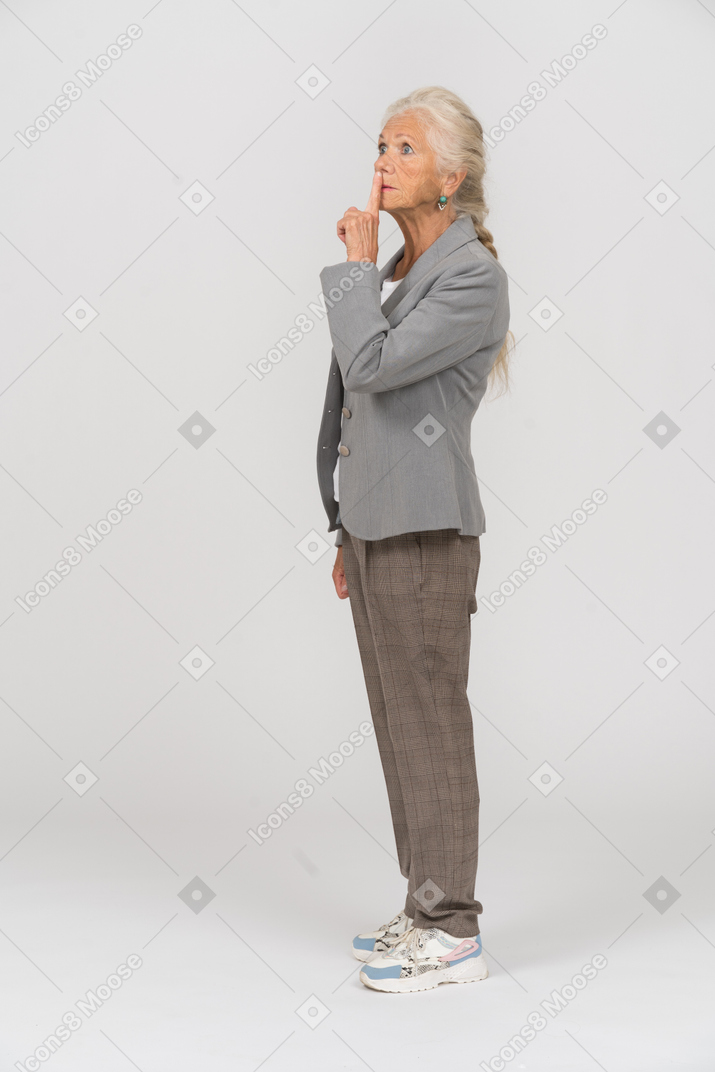 Vista lateral de una anciana haciendo un gesto de shh