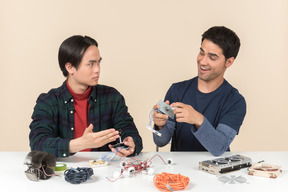Zwei junge geeks sitzen am tisch und reparieren ein paar details