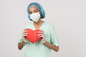 Женщина-врач держит сердце макет