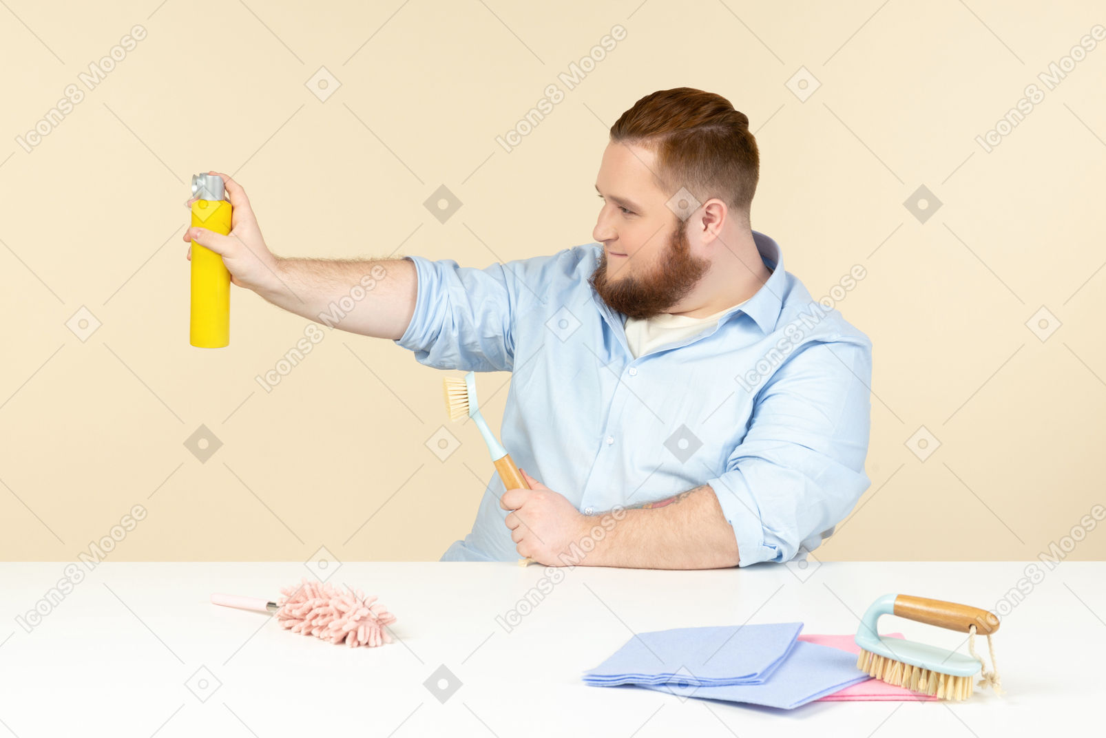 Giovane casalinga in sovrappeso seduto al tavolo e in possesso di spray per la pulizia