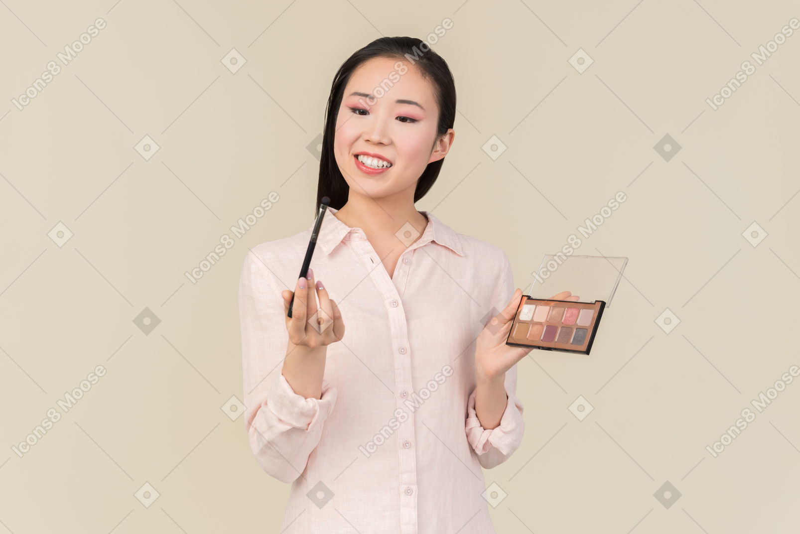 Young asian woman looking closely at brush while applying eyeshadows