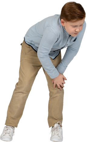 一个男孩弯下腰，触摸受伤的膝盖的正面图