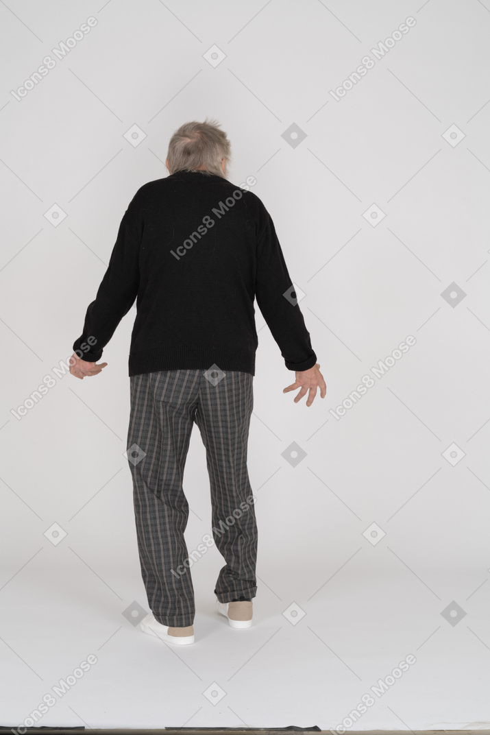 Back view of old man standing with spread hands