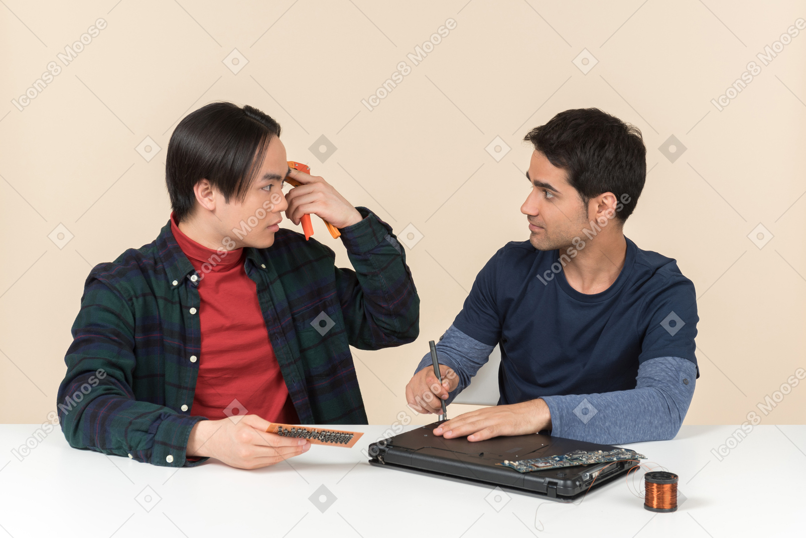 Two young geeks sitting at the table and having issues with fixing the laptop