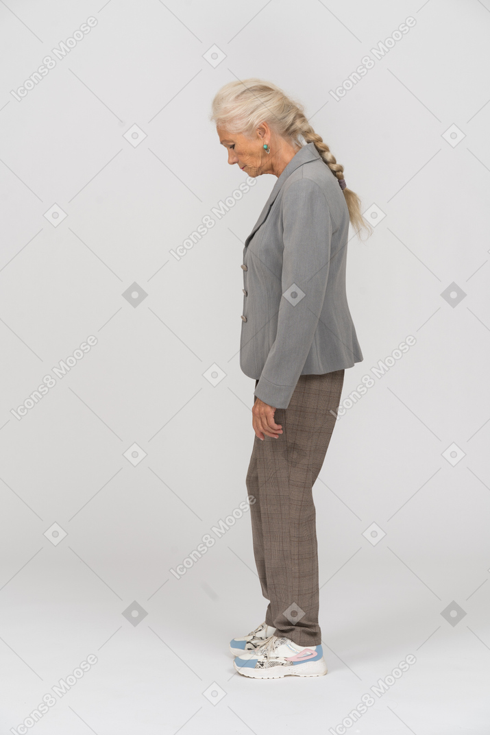 Vista lateral de una anciana en traje mirando hacia abajo