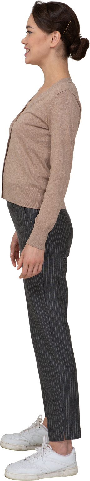 Vista laterale di una donna sorridente in pullover e pantaloni