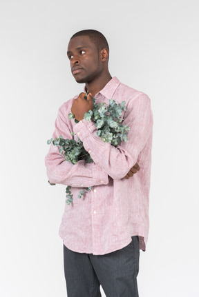 Good looking young man holding green branches