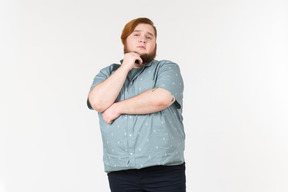 Pensive young overweight man standing with hands crossed