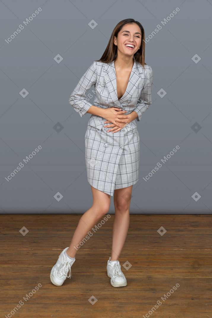 Young woman laughing out loud and holding her belly with both hands