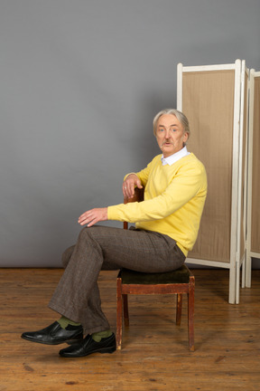 Middle-aged man sitting on chair and looking at camera