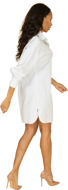 Vista posteriore di tre quarti di una giovane donna dalla carnagione scura in abito bianco