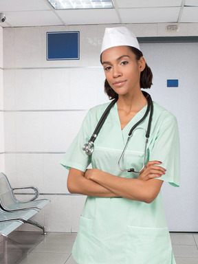 A woman in scrubs and a stethoscope standing in a hospital
