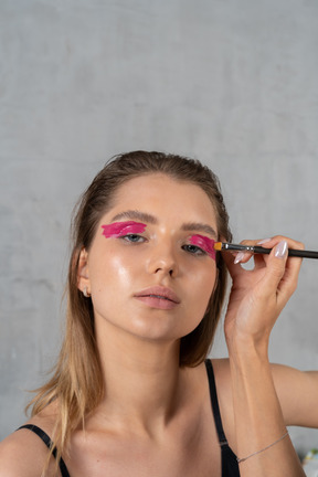Foto de una mujer joven que se maquilla los ojos