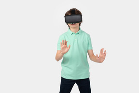 Niño con casco de realidad virtual tocando una pared imaginaria