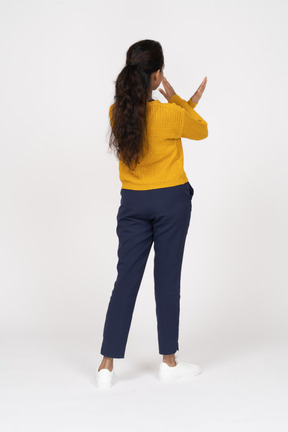 Rear view of a girl in casual clothes showing stop gesture