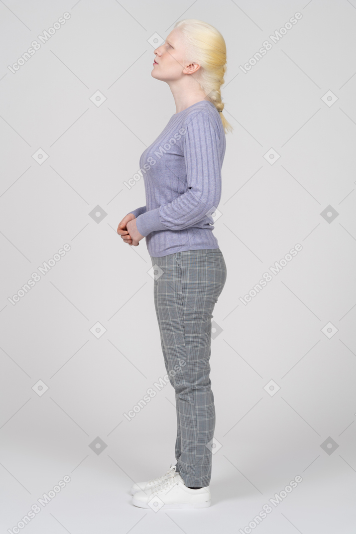 Vue latérale d'une femme regardant vers le haut avec ses mains jointes