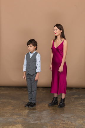 Woman in red dress and little boy standing in profile