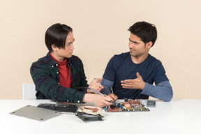 Dos jóvenes geeks con algunos detalles sobre la mesa que tienen algunos problemas
