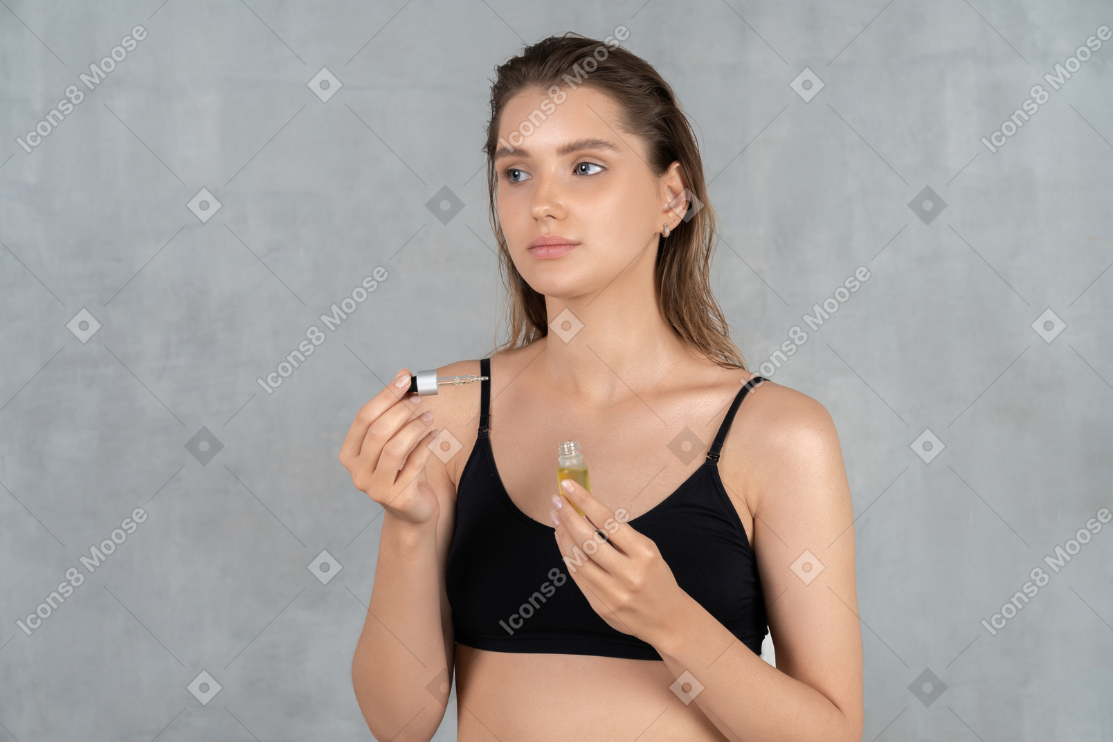 Vista frontal de uma jovem segurando a garrafa de óleo facial