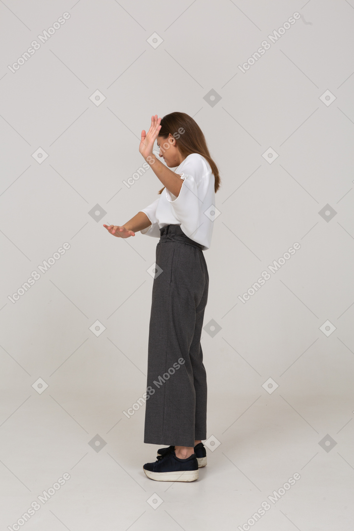 Vista laterale di una giovane donna riluttante in abiti da ufficio che allunga il braccio