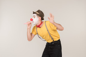 Male clown blowing into plastic straw