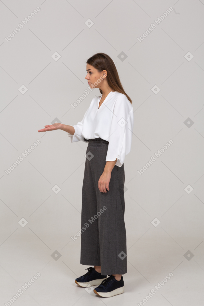 Vista de tres cuartos de una joven en ropa de oficina pidiendo algo