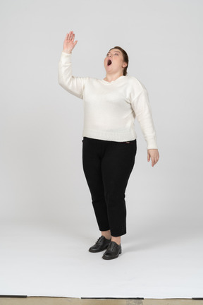 Front view of an impressed plus size woman in casual clothes pointing up with a hand