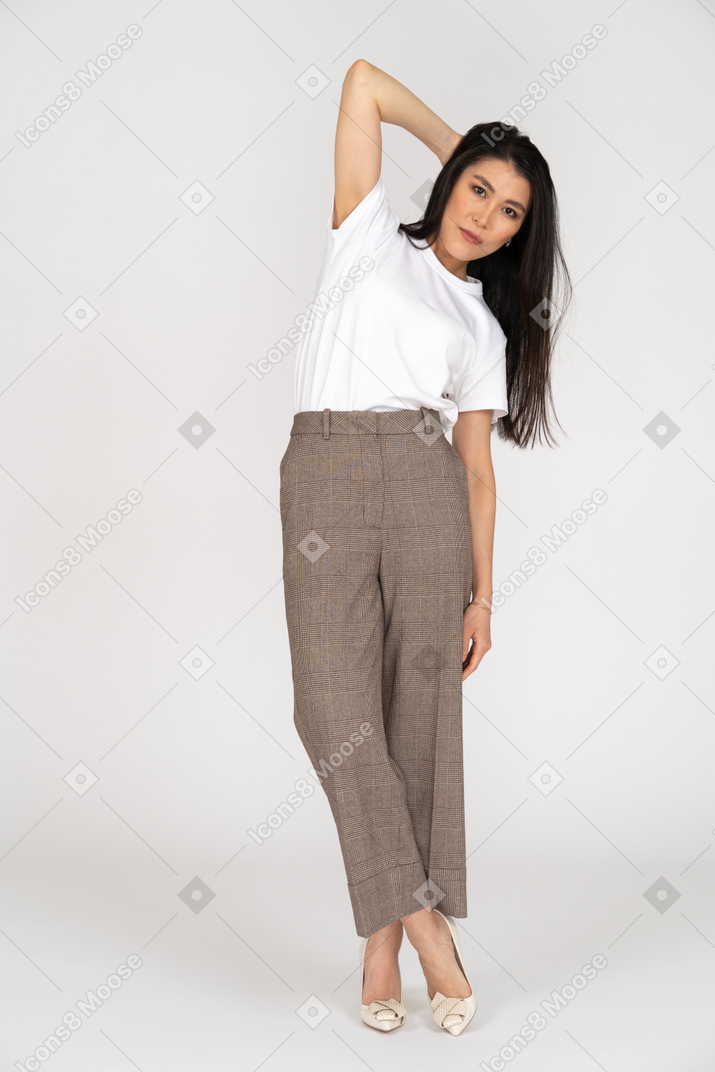 Front view of a young woman in breeches touching head