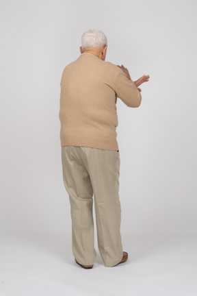 Retrovisione di un uomo anziano in abiti casual che mostra il gesto di arresto