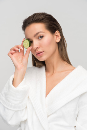 Beautiful young woman holding cucumber slice