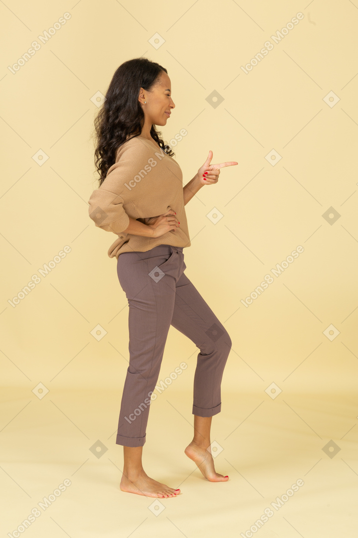 Side view of a supportive young dark-skinned female pointing finger