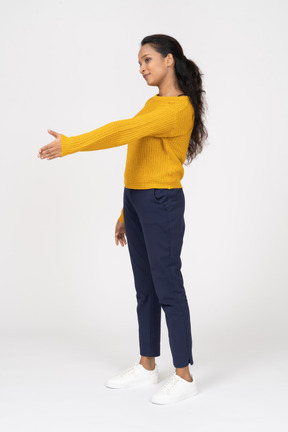 Vista lateral de una niña en ropa casual dando una mano para agitar